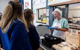 Picture_of_two_girls_in_a_school_canteen_with_a_catering_assistant_serving_them_at_till